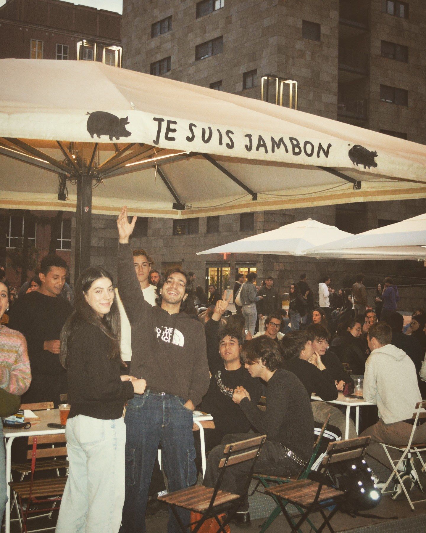 La piazza piena di gente sotto l’ombrellone di Je Suis Jambon, di sera