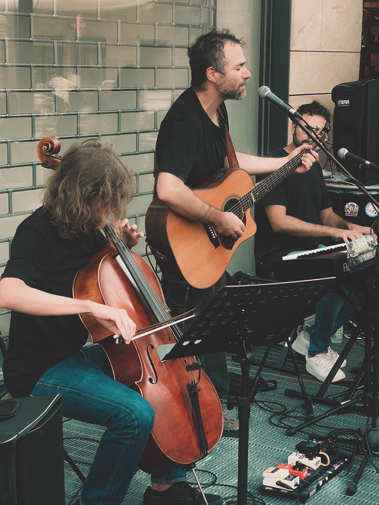 Un trio con violoncello, chitarra e tastiera suona davanti al locale